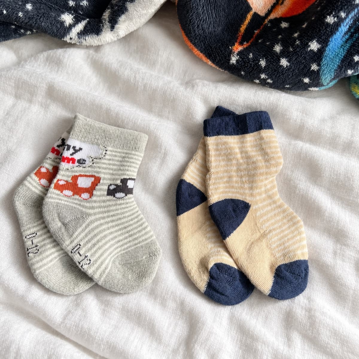 Car-print and striped baby socks, two pairs on cream linen