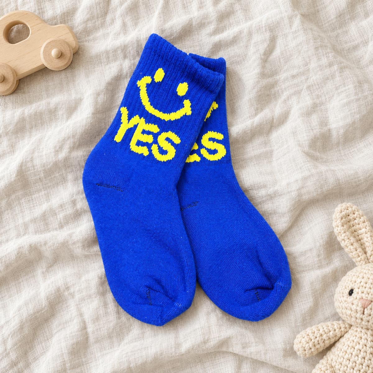 Royal-blue socks with a yellow smiley face and YES on cream linen with nursery props