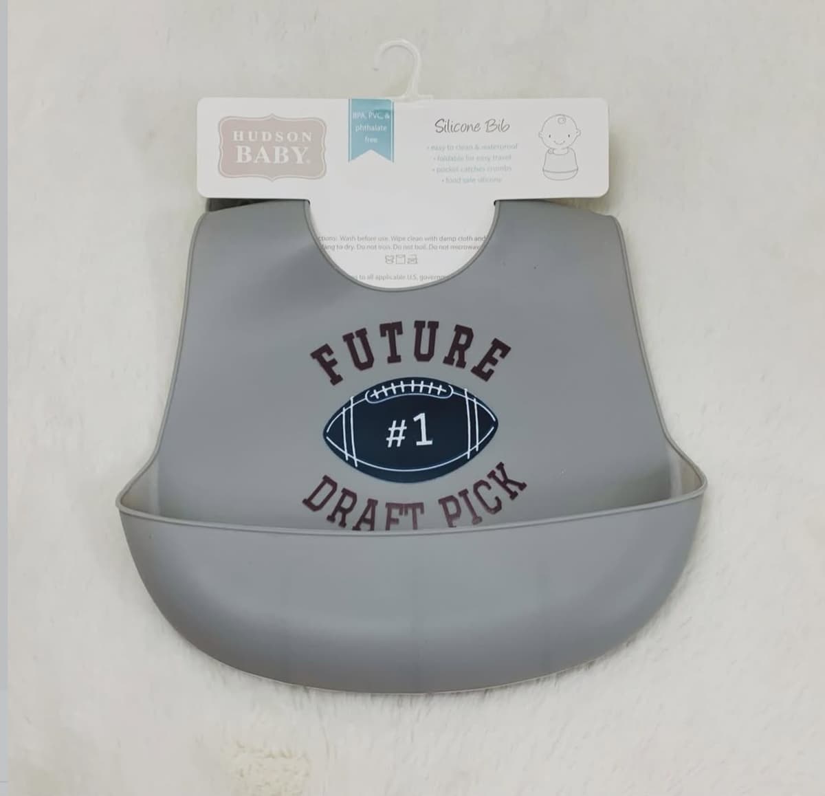 Grey Hudson Baby silicone bib with a crumb pocket, printed Future #1 Draft Pick with a navy football, on white fur