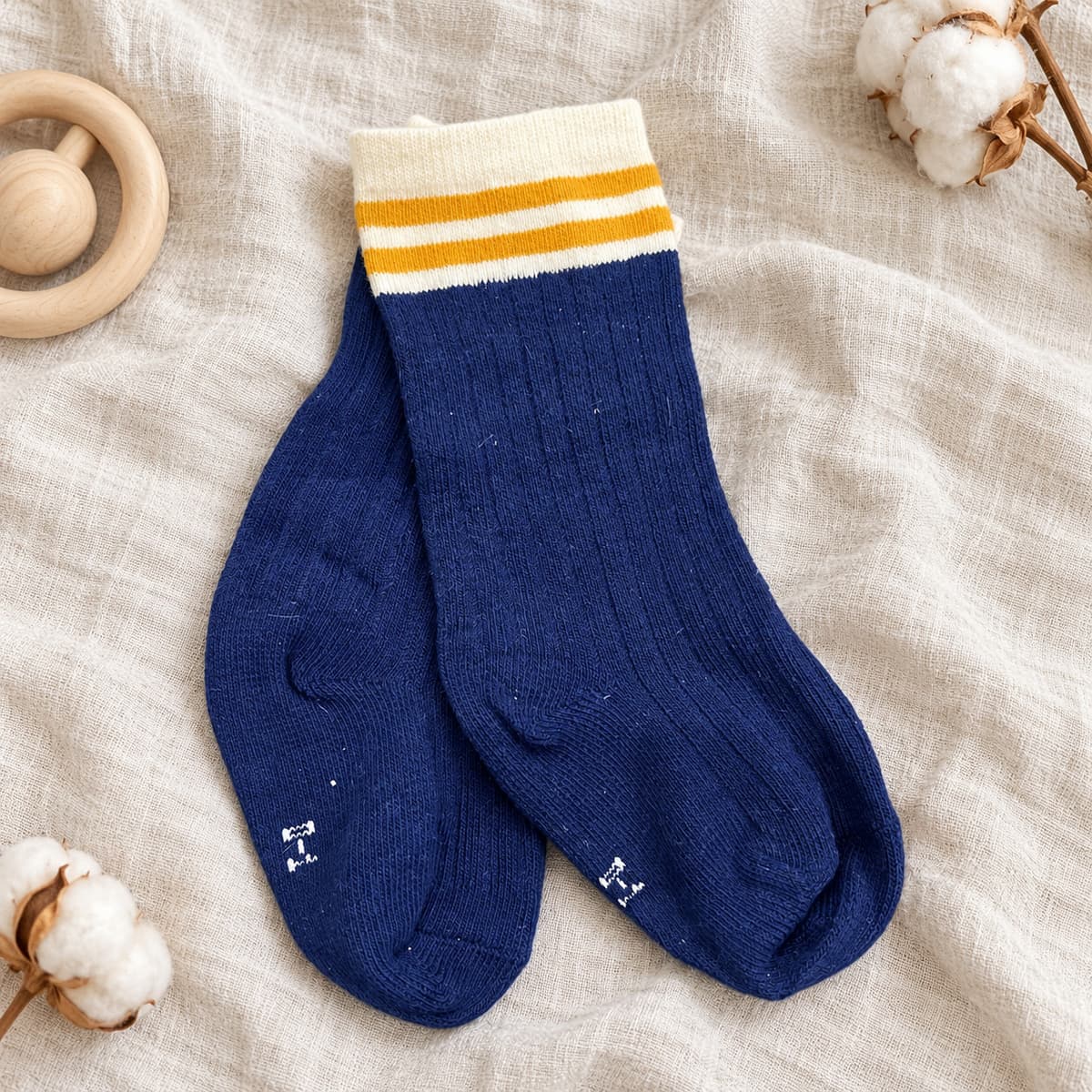Navy ribbed socks with a cream cuff and mustard stripes on cream linen with nursery props