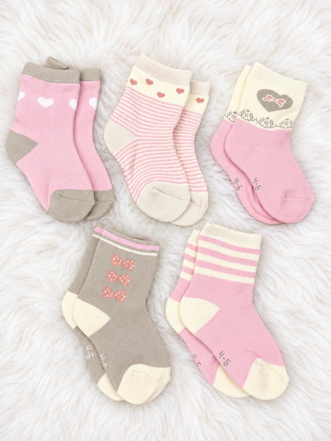 Five pairs of girls' socks in pink, cream and grey: white hearts, pink stripes with red hearts, a grey heart with a bow, pink bows on grey, and pink and cream stripes