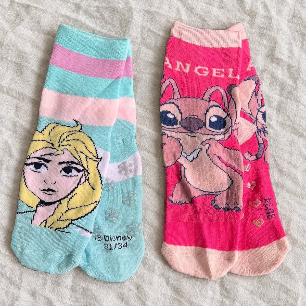 Pink Angel socks and aqua Frozen socks on linen