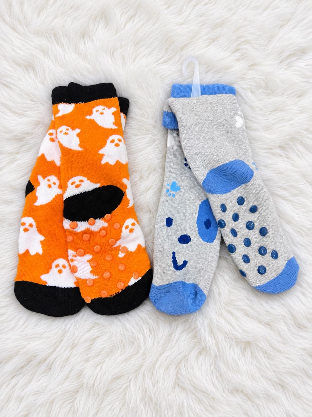 Two pairs of towel-padded socks with grip dots: orange with white ghosts, and grey with a blue puppy face